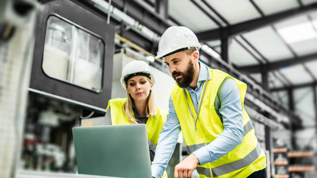Deux responsables examinent les données d'inspection sur un ordinateur portable en atelier